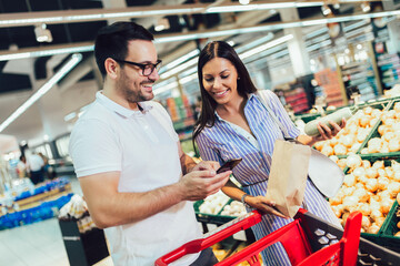 Happy couple buying vegetables at grocery store or supermarket - shopping, food, sale, consumerism