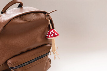 Brown part leather backpack with a mushroom-shaped keychain. The concept of travel, vacation, road, school education.