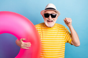 Portrait of elderly retired cheerful man holding rubber ring having fun resort isolated over bright...