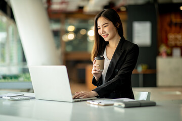Portrait of Businesswoman working on laptop computer doing finances,accounting analysis,report,data and pointing graph at the office.