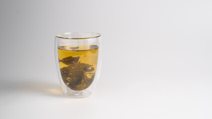 Green tea leaves in a transparent cup. Background with a cup of tea and copy space.