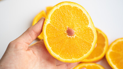 Hand taking a slice of orange from the table. Juicy orange circle in a hand. Orange circle like a sun