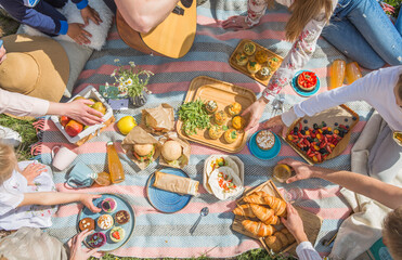 Picnic setting with burgers, tart, croissant, cakes, picnic hamper basket, guitar and food ready...