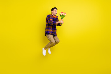 Full length profile side photo of young handsome man happy smile jump hold flowers bouquet isolated...