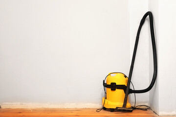 Big yellow construction vacuum cleaner stands on wooden parquet floor