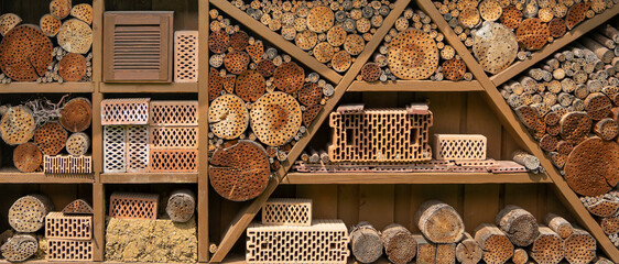 Großes breites Insektenhotel in Form eines Regals, gefüllt mit Holz und Ziegelsteinen