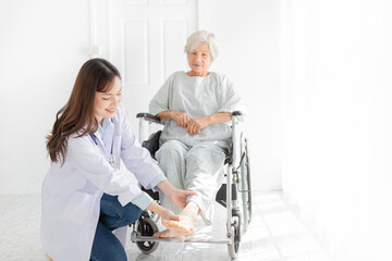 asian female doctor holding leg of old stroke patient in hospital, elderly rehabilitation clinic, they training to rehab muscle, foot screening