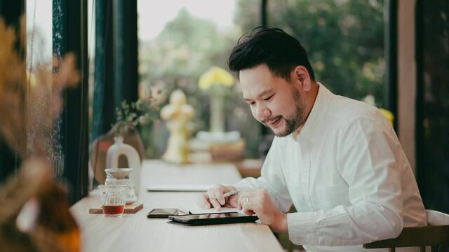 Young businessman is working with documents, writing and technology communication cellphone and tablet at table in cafe interior. Successful businessman is working.