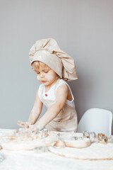 a happy child in an apron and a chef's hat prepares dough