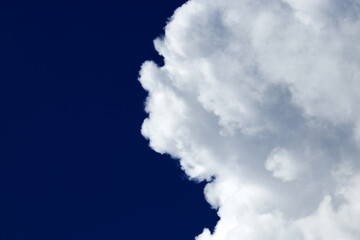 White fluffy cloud on a dark blue sky - cloudscape, overcast - cloudscape background