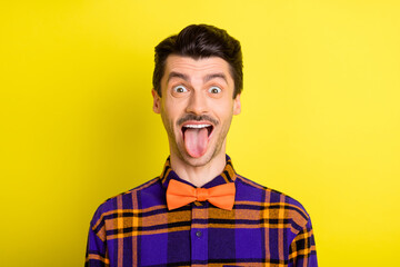Photo of young man happy positive smile fooling grimace tongue-out silly funny isolated over yellow color background