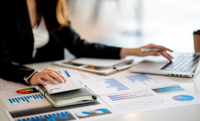 Close up Business woman using calculator and laptop for do math finance on wooden desk, tax, accounting, statistics and analytical research concept