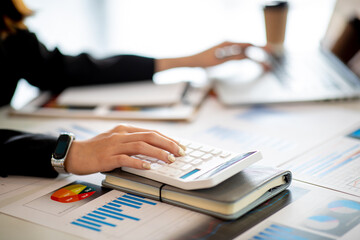 Close up Business woman using calculator and laptop for do math finance on wooden desk, tax, accounting, statistics and analytical research concept