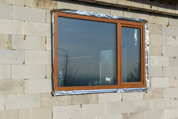 Wall of a house under construction. Foam concrete blocks, wooden frame window.