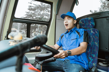 A male bus driver in blue uniform gets shocked while driving the bus