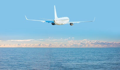 Fototapeta na wymiar Airplane flying over tropical sea at beautiful cloudy sky