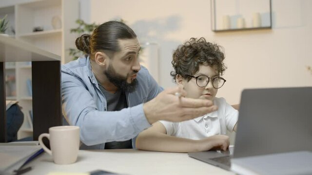 Puzzled father helping son with difficult home assignment, distance education