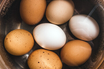 A pile of boiled chicken white and brown eggs in water, close-up