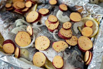 Mediterranean seafood. gilt-head sea bream fish dorado. Three Raw fish fillet on lemon slices Dorada with sweet potato pieces in foil for baking, food background. top view. Healthy food concept.