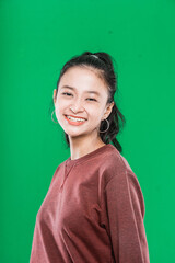 Close up beautiful young asian woman smiling and looking at camera isolated on green background