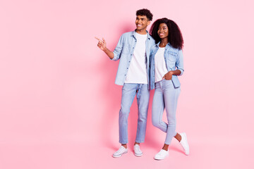 Full size portrait of two positive dark skin persons look indicate finger empty space isolated on pink color background