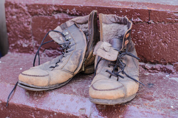 A pair of old, shabby brown lace-up boots stands on the steps.
