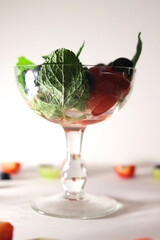 summer fruit cocktail with mint leaves close-up in a glass vase