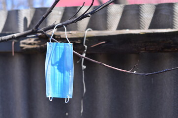 A medical mask hangs on a tree branch.