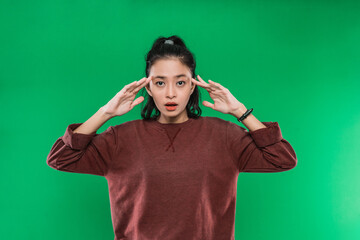 portrait young woman surprised expression raised her hand while holding his head and looked confused on green background