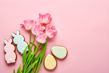 Fototapeta na wymiar Pink tulips with easter gingerbread eggs located in a row on pink background. Floral pattern. Mock up and banner. Space for text.