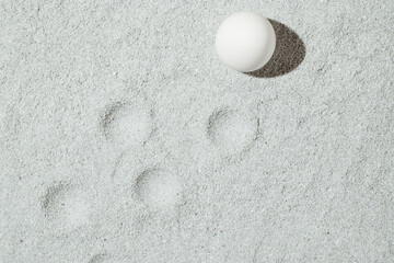 Minimal Easter concept with a brown egg and traces on the sand. Summer and holiday idea. Flat lay.