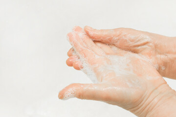 An adult woman's hands lathered with soap, close-up. Hand washing and domestic hygiene concept