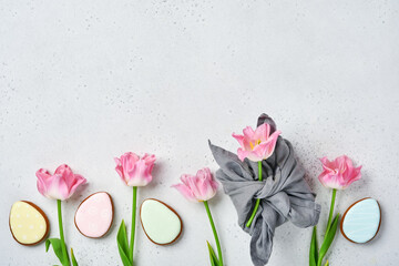 Pink tulips with easter gingerbread eggs located in a row on grey background. Floral pattern. Mock up and banner. Space for text.