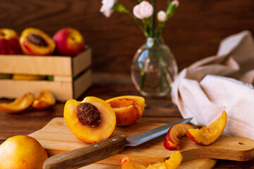 sliced nectarines on a chopping board on a wooden table. halves and slices of sweet peach in the kitchen