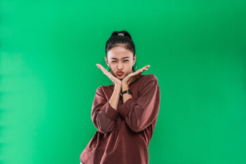 Beautiful Asian woman smiling fish face while raising two hands that are placed on the chin against green background