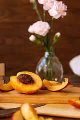 sliced nectarines on a chopping board on a wooden table. halves and slices of sweet peach in the kitchen
