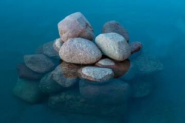 Góra kamieni zanurzona do połowy w błękitnej wodzie.