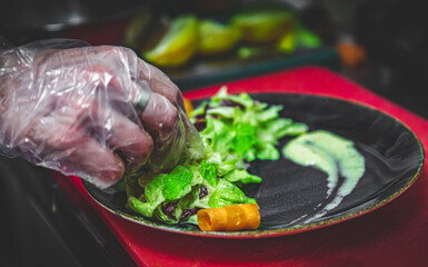 chef hand of cook in gloves making vegetables salad on kitchen