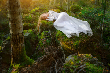 Beautiful young woman in a white dress in the middle of a forest