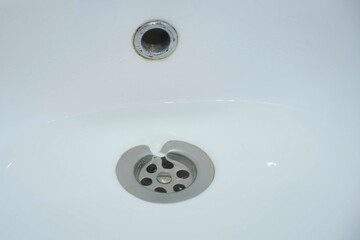 Water is draining in drain hole of the sink in bathroom, closeup view. Bath clogging and repairing...
