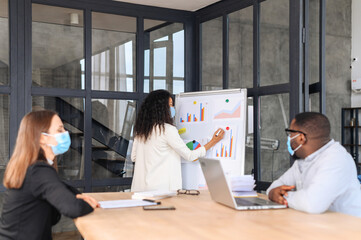New normal business practice of business people wearing medical mask, face shield sitting together work in office, keep social distancing from others, discuss the achievements or ways of development