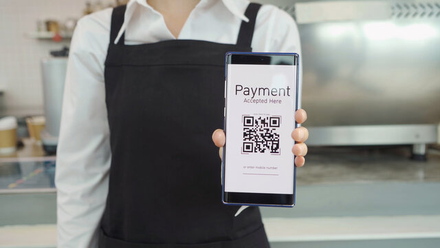 Close up of woman hand holding a smartphone QR code screen scanning in cafe restaurant, quick response online convenience payment process. Internet banking. Online wallet. Cashless. Business service.