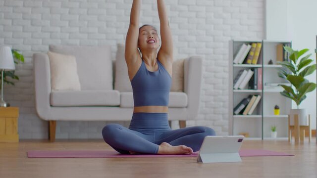 Asian Yoga Coach Athlete woman teaching in yoga class video conference streaming online with students in class isolation at home to meditation and relaxation due virus pandemic,New wellness at home