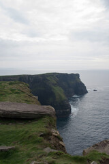Fototapeta na wymiar Cliffs of Moher on a rainy day. Green fields and calm water. Ireland, Europe