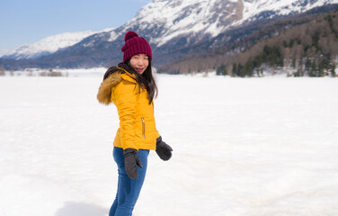 Fototapeta na wymiar winter holidays - young happy and attractive Asian Korean woman enjoying playful on snow at beautiful Swiss Alps landscape during Christmas vacation trip
