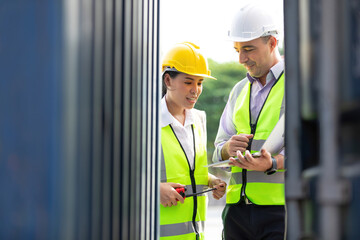 factory workers or engineers using laptop computer and talking about project work in containers warehouse storage