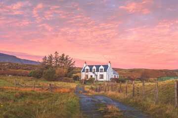 Vibrant, pink colourful sunset or sunrise sky over traditional, rural country croft house in idyllic countryside at Staffin on the Isle of Skye, Scottish Highlands, Scotland. - obrazy, fototapety, plakaty