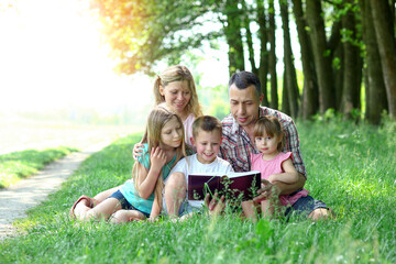 Fototapeta premium young family reading the Bible in nature