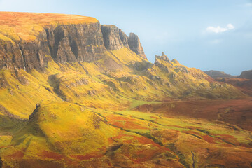 Vibrant golden light at sunset or sunrise over colourful landscape view of the rugged, otherworldly terrain of the Quiraing on the Isle of Skye, Scotland.