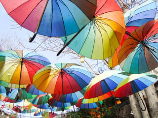 Fototapeta na wymiar festive street decoration. multicolored umbrellas on a blue sky background